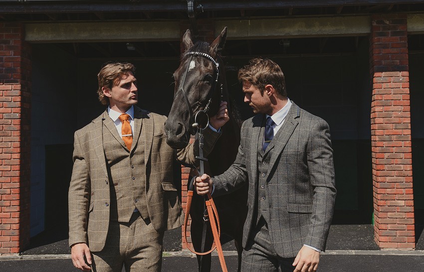 Two men walking a black horse